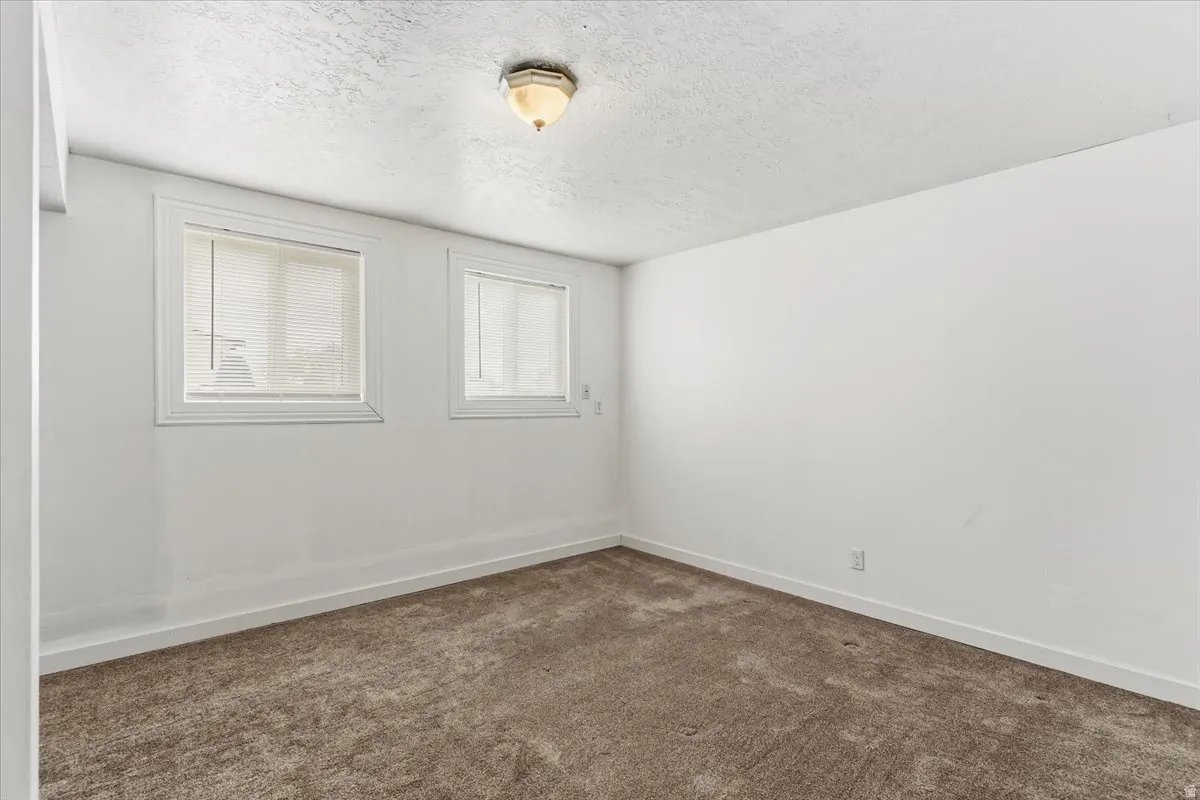 Spare room featuring dark carpet and a textured ceiling