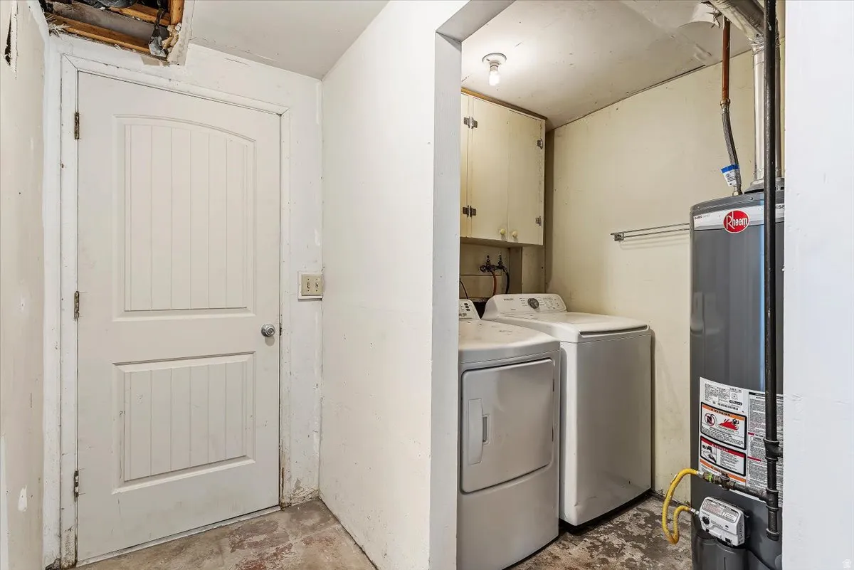 Laundry room with concrete flooring, water heater, independent washer and dryer, and cabinet space