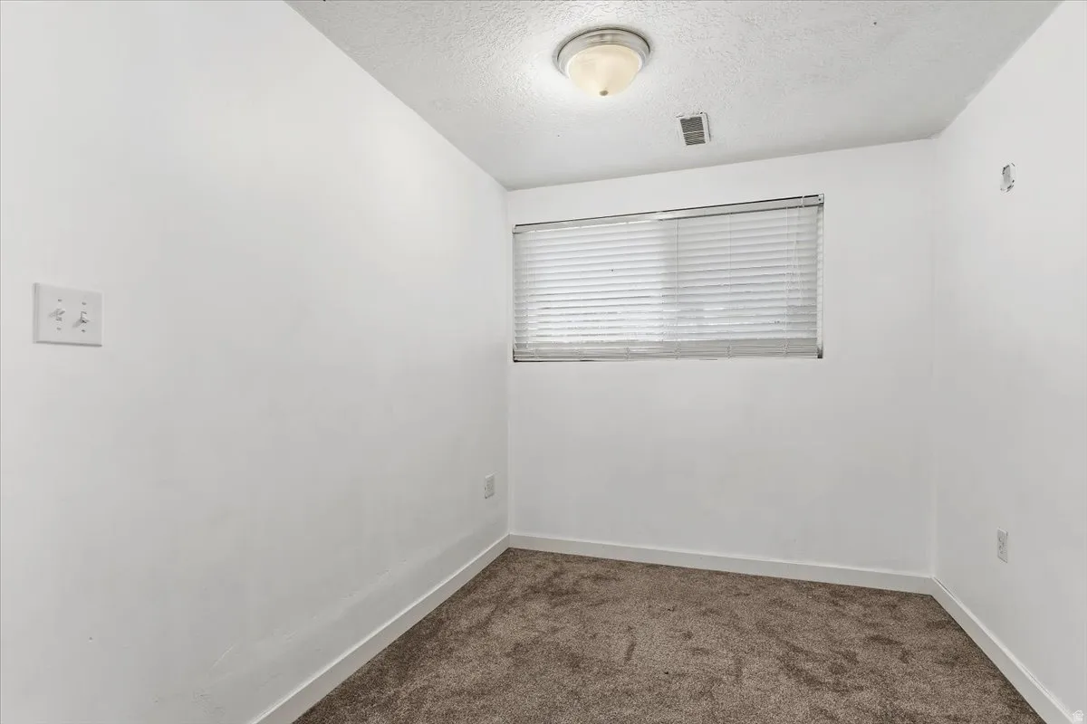 Empty room featuring a textured ceiling and dark carpet