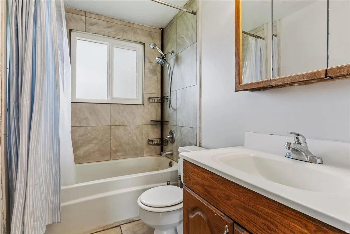 Bathroom featuring vanity and shower / bathtub combination with curtain