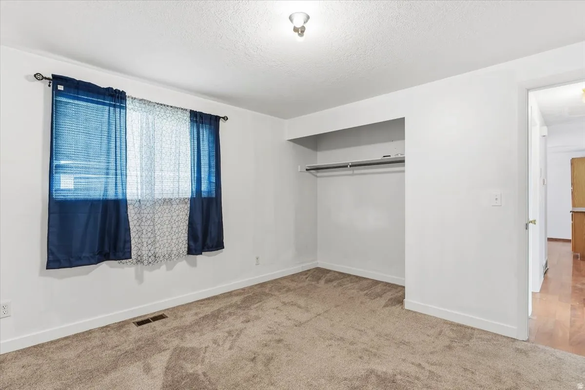 Unfurnished bedroom with carpet, a closet, and a textured ceiling