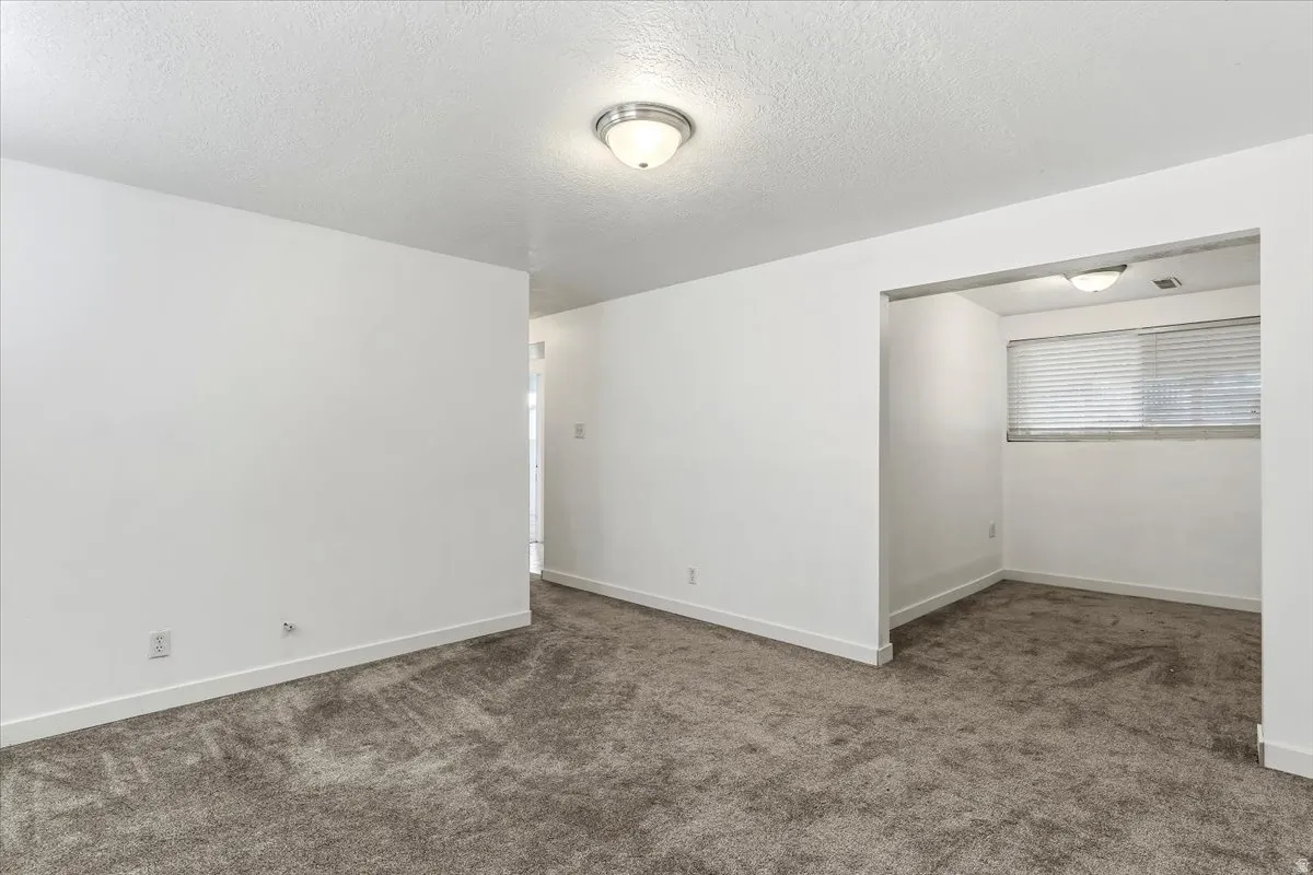 Unfurnished room with a textured ceiling and dark carpet