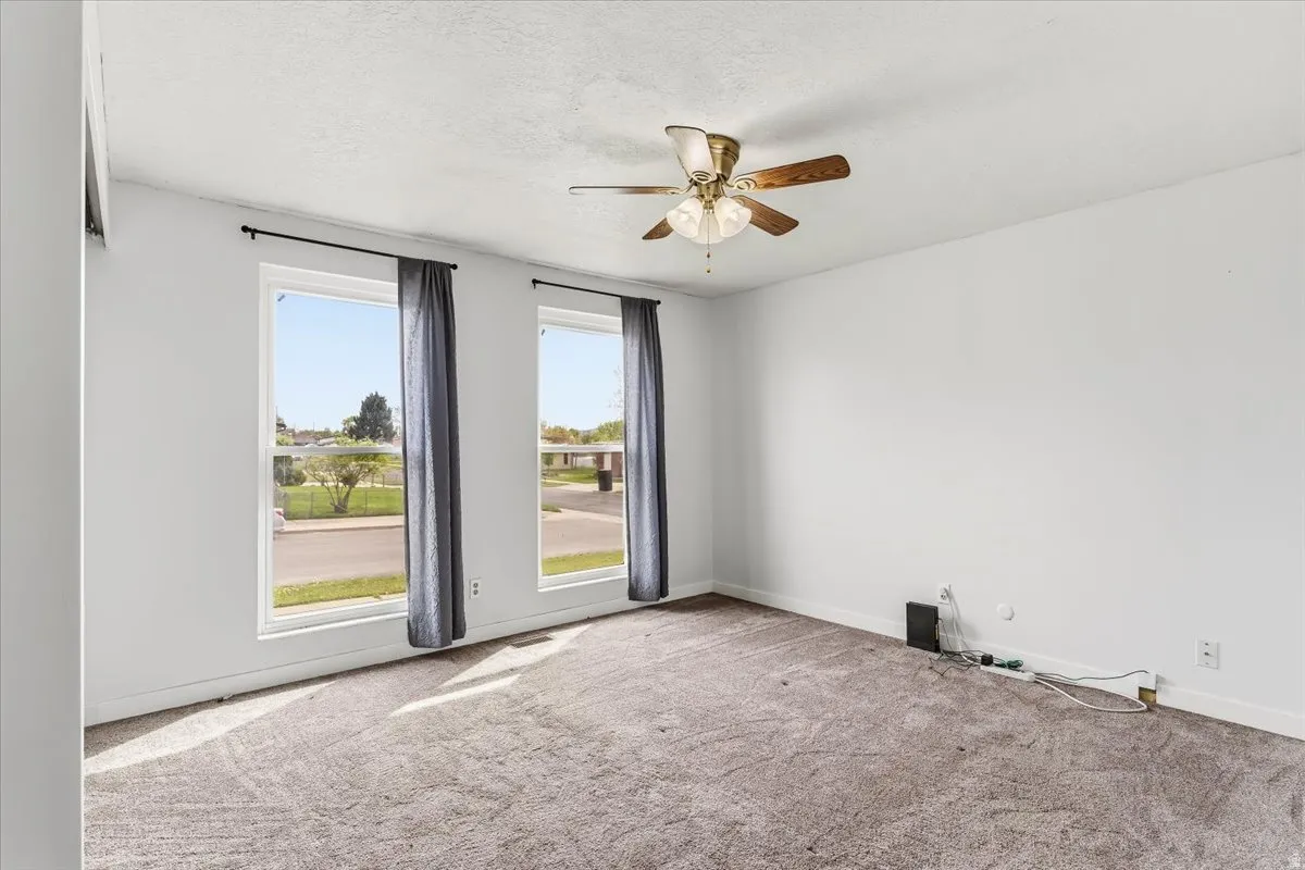 Spare room with carpet floors, ceiling fan, and a textured ceiling