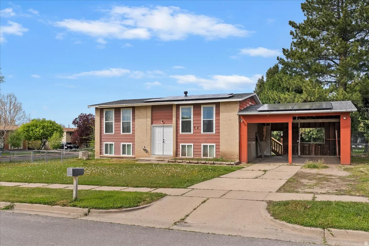 View of front of house with roof mounted solar panels, a carport, and concrete driveway