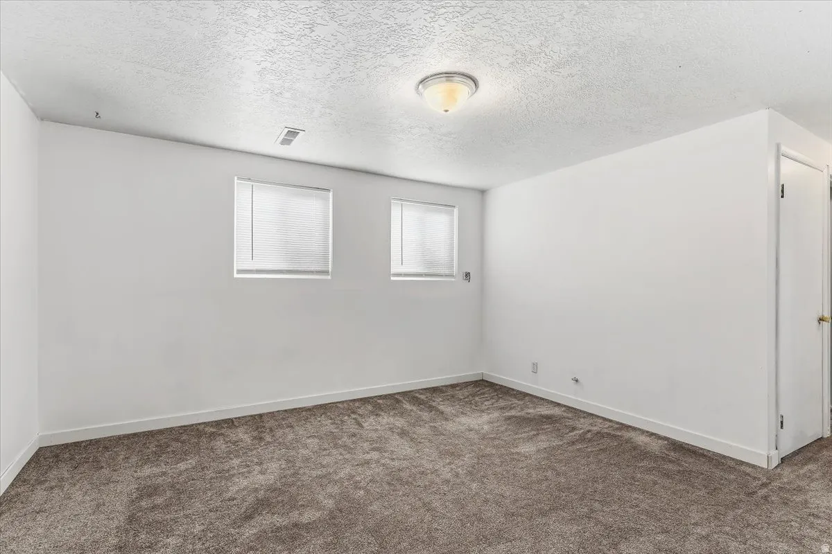 Spare room with dark carpet and a textured ceiling