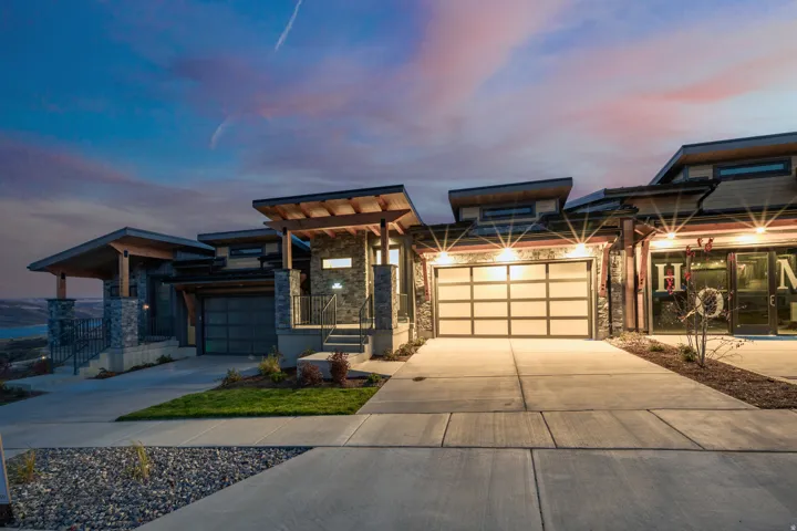 View of front of house featuring stone siding, driveway, and an attached garage