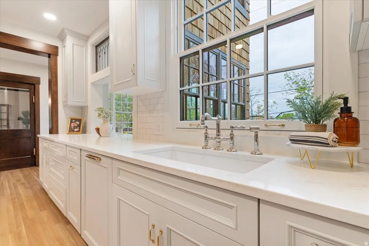 Kitchen featuring white cabinetry, light stone countertops, light wood-style floors, decorative backsplash, and recessed lighting