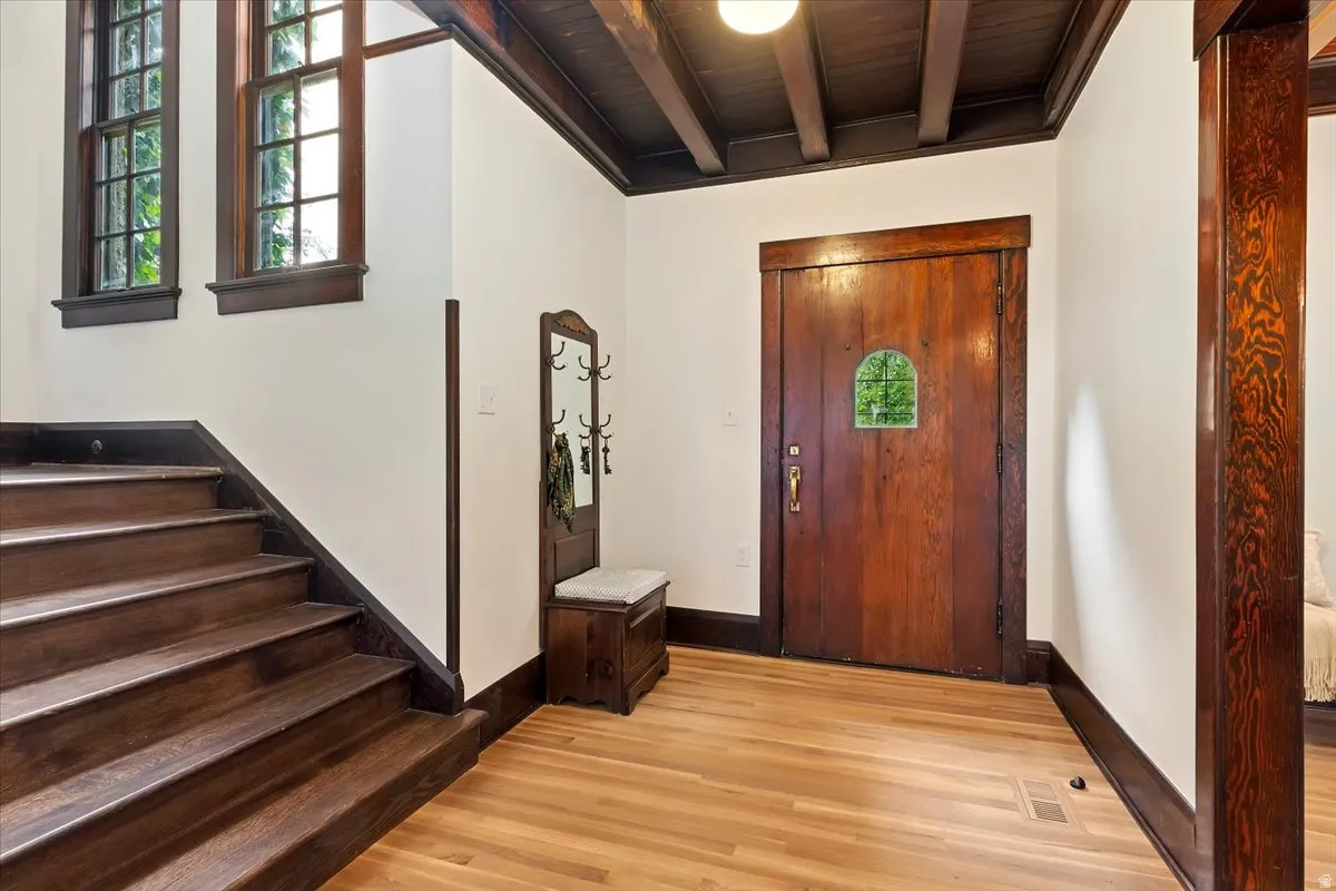 Foyer entrance featuring light wood-type flooring, healthy amount of natural light, and a wooden ceiling with exposed beams