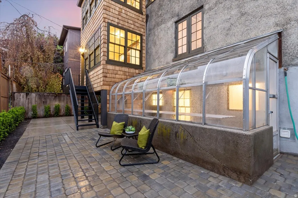 Back of property with a sunroom, a patio, and stucco siding