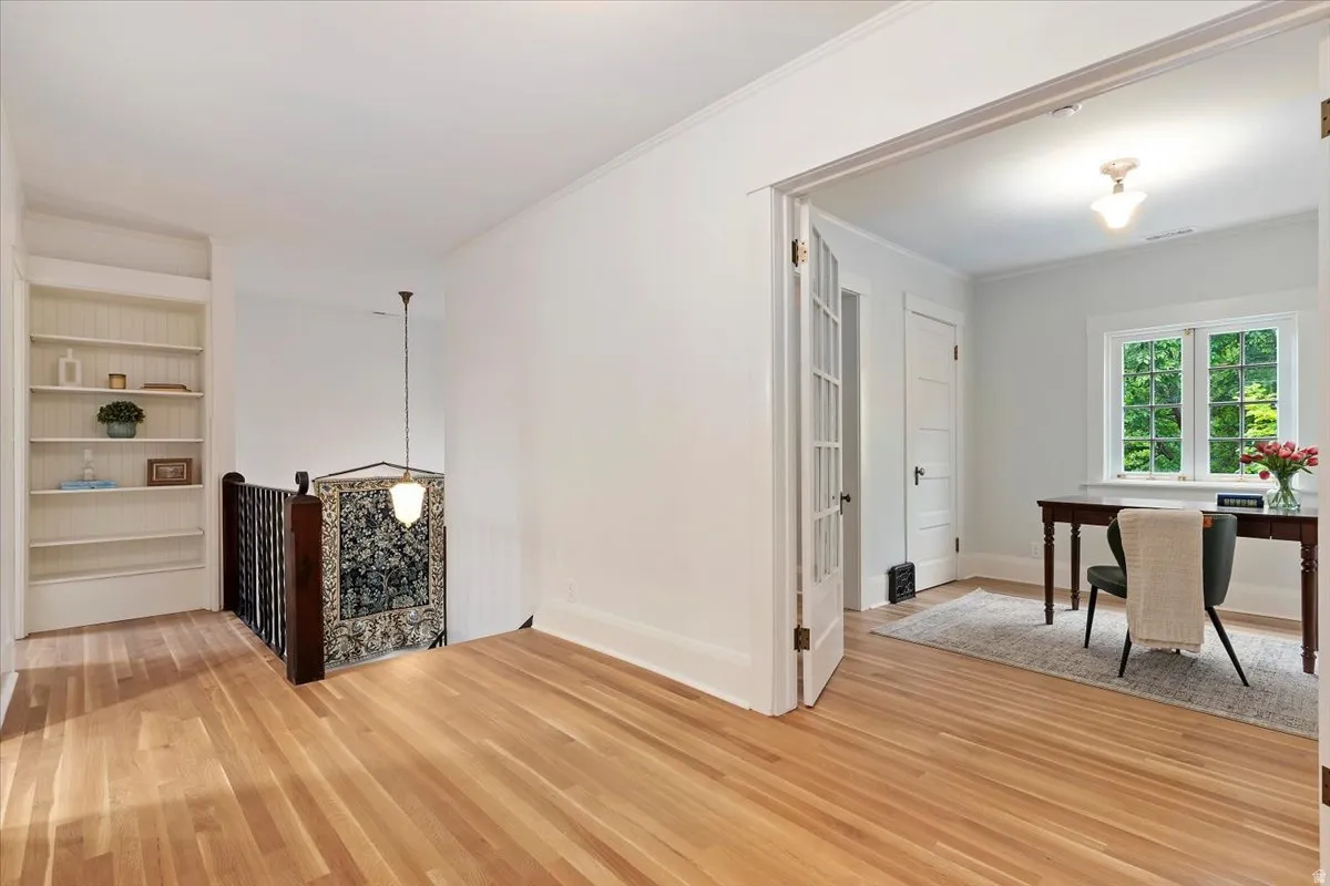 Living area featuring built in features, ornamental molding, and light wood finished floors