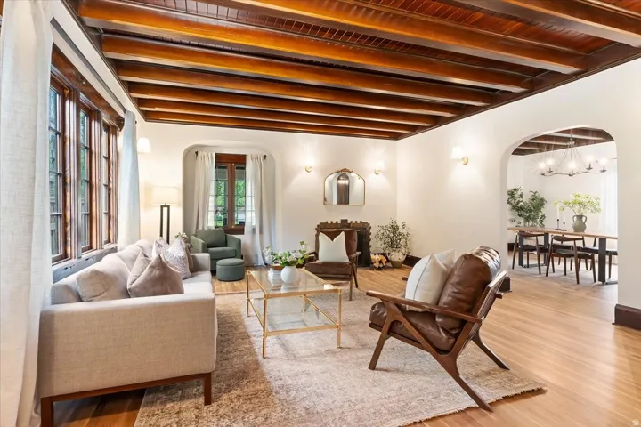 Living area featuring arched walkways, wood finished floors, beam ceiling, and hanging lights