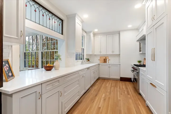 Kitchen featuring double oven range, light wood-style floors, white cabinetry, recessed lighting, and backsplash