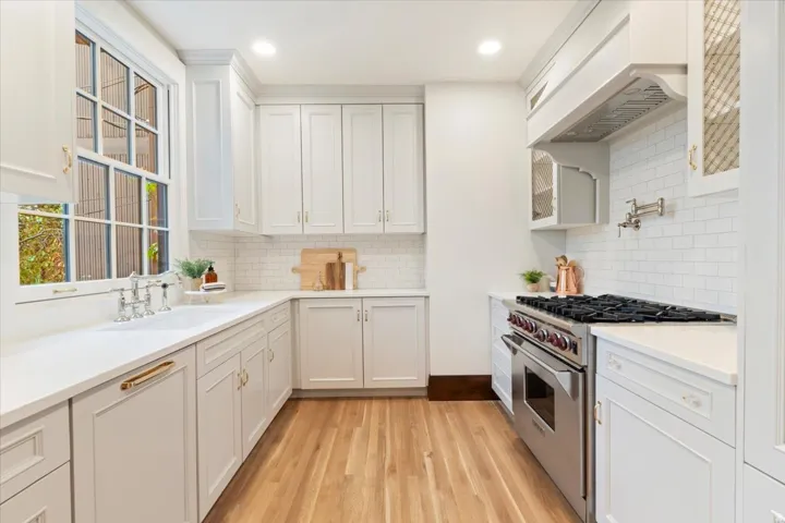Kitchen featuring stainless steel stove, white cabinets, light wood-style flooring, light stone counters, and recessed lighting