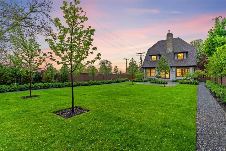 Back of property at dusk with a fenced backyard and a chimney