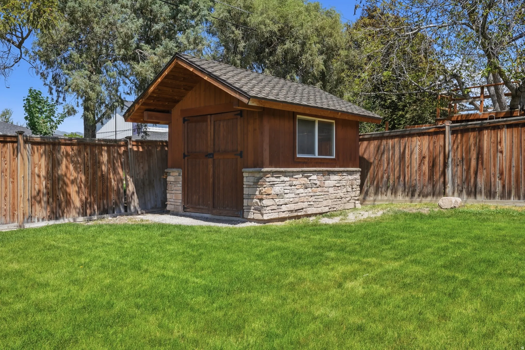 Detached shed with stone veneer base and wood siding