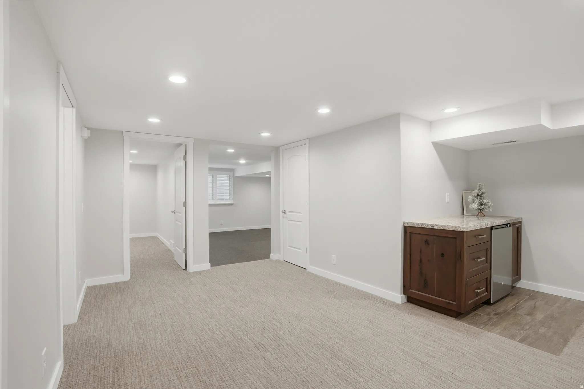 Bar featuring recessed lighting, light stone countertops, dark wood finish cabinetry, stainless steel refrigerator, and light carpet