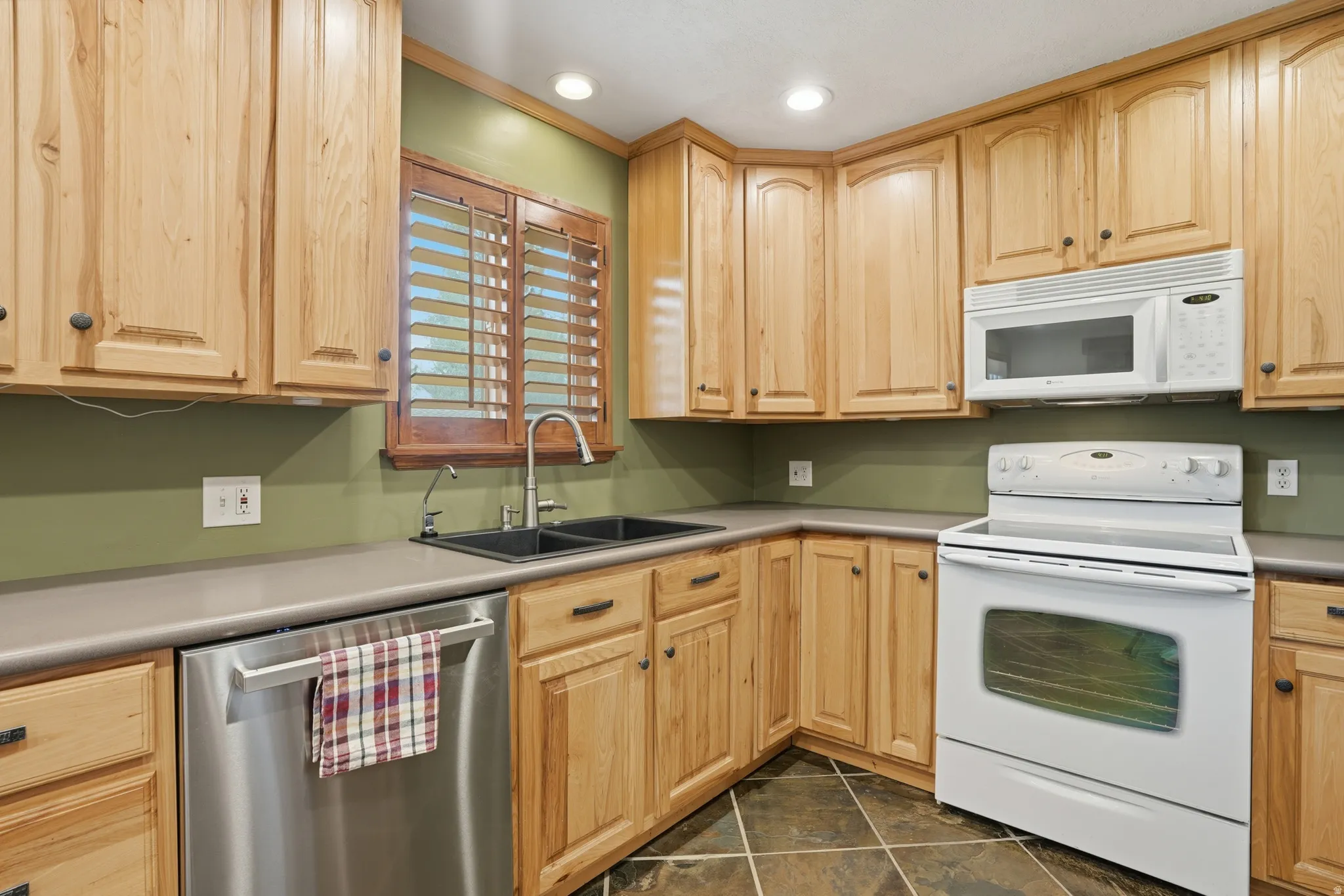 Kitchen with white appliances, light wood finish cabinetry, light countertops, and recessed lighting