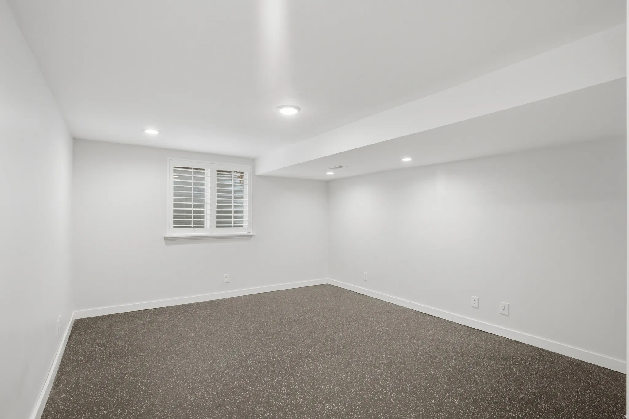 Finished basement exercise room with dark flooring and recessed lighting