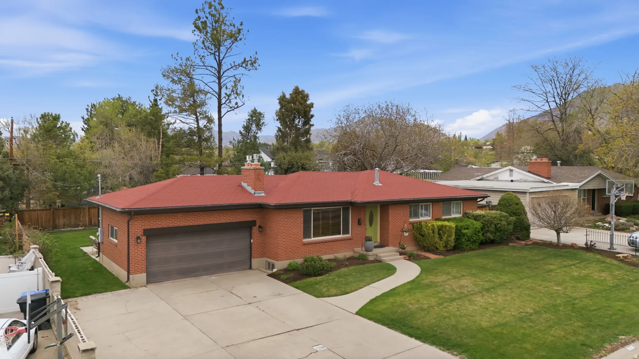 Rambler-style house featuring brick siding, an attached garage, concrete driveway, and a chimney
