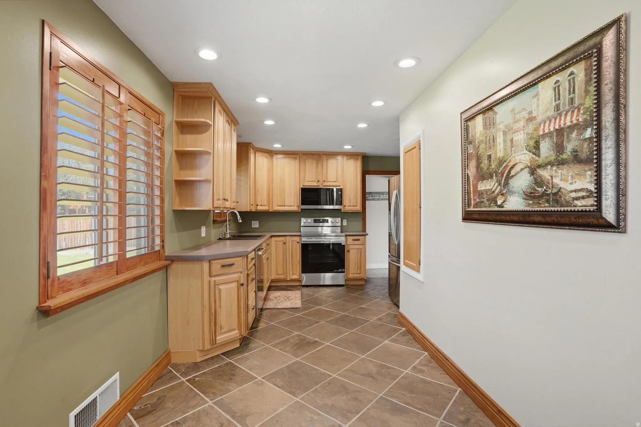 Kitchen featuring wood cabinetry, stainless steel appliances, recessed lighting, and tile flooring