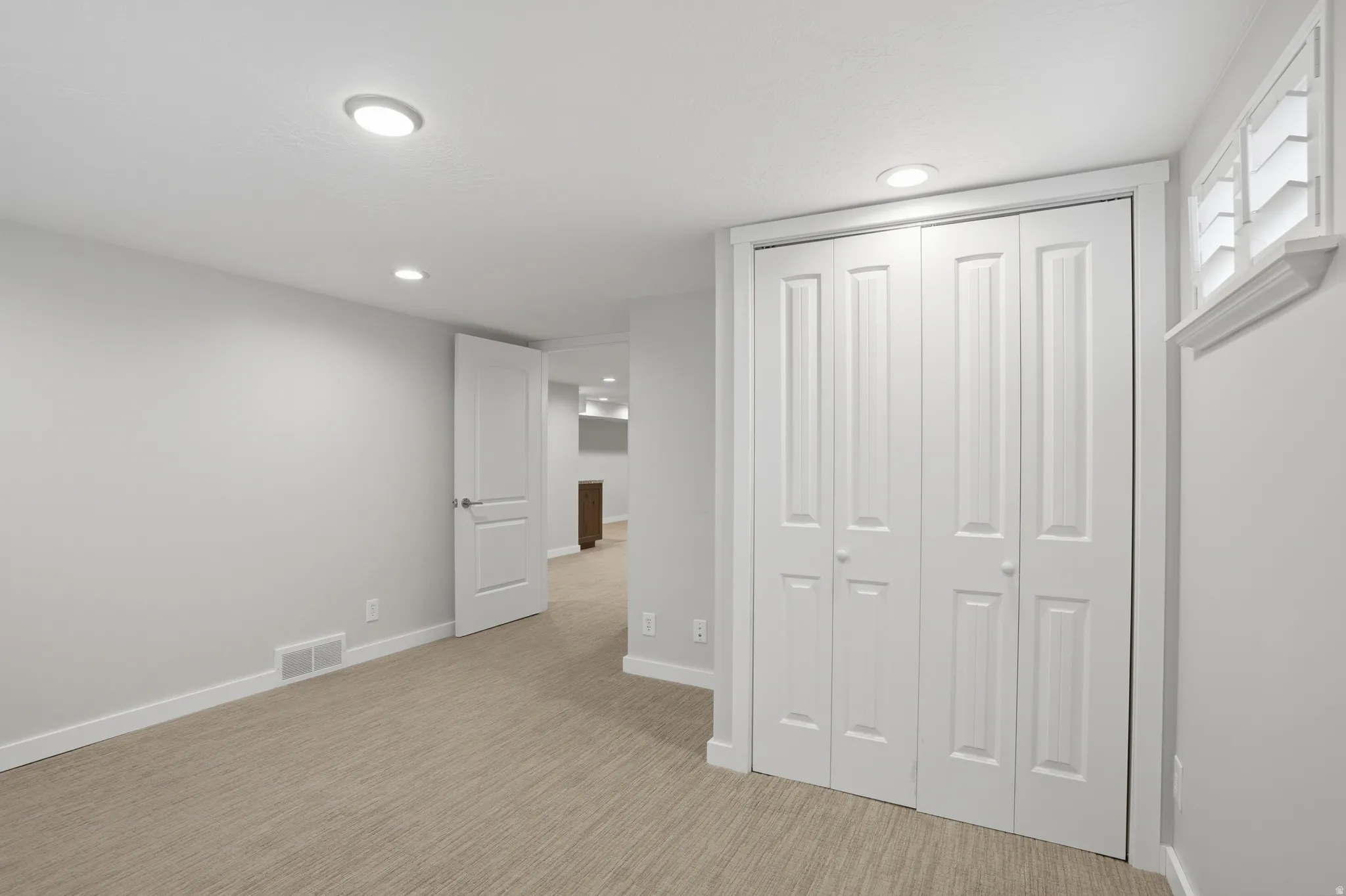 Unfurnished bedroom with a closet, light colored carpet, and recessed lighting