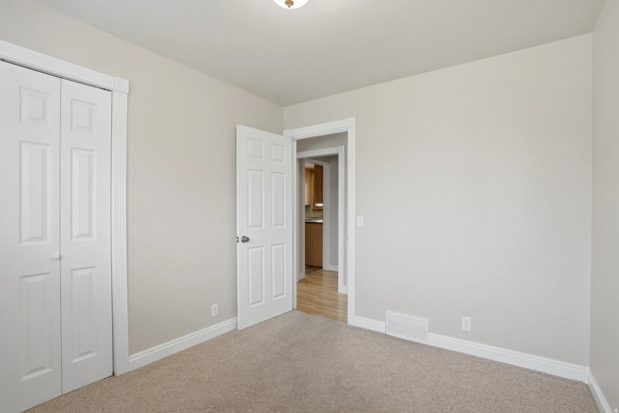 Unfurnished bedroom with light colored carpet and a closet