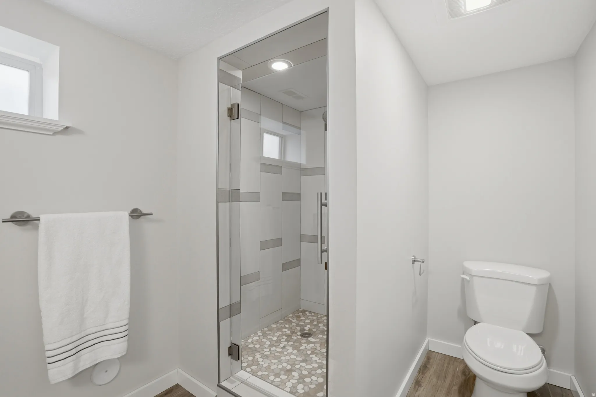 Full bathroom with a shower stall and light wood-style floors
