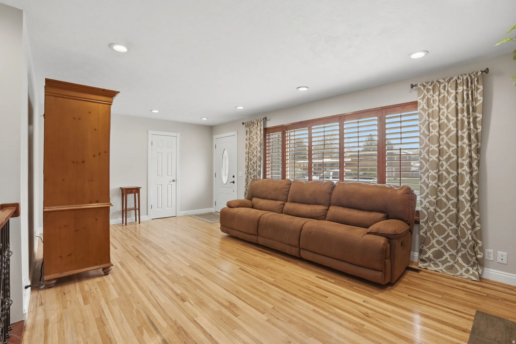 Living area with light wood-type flooring and recessed lighting