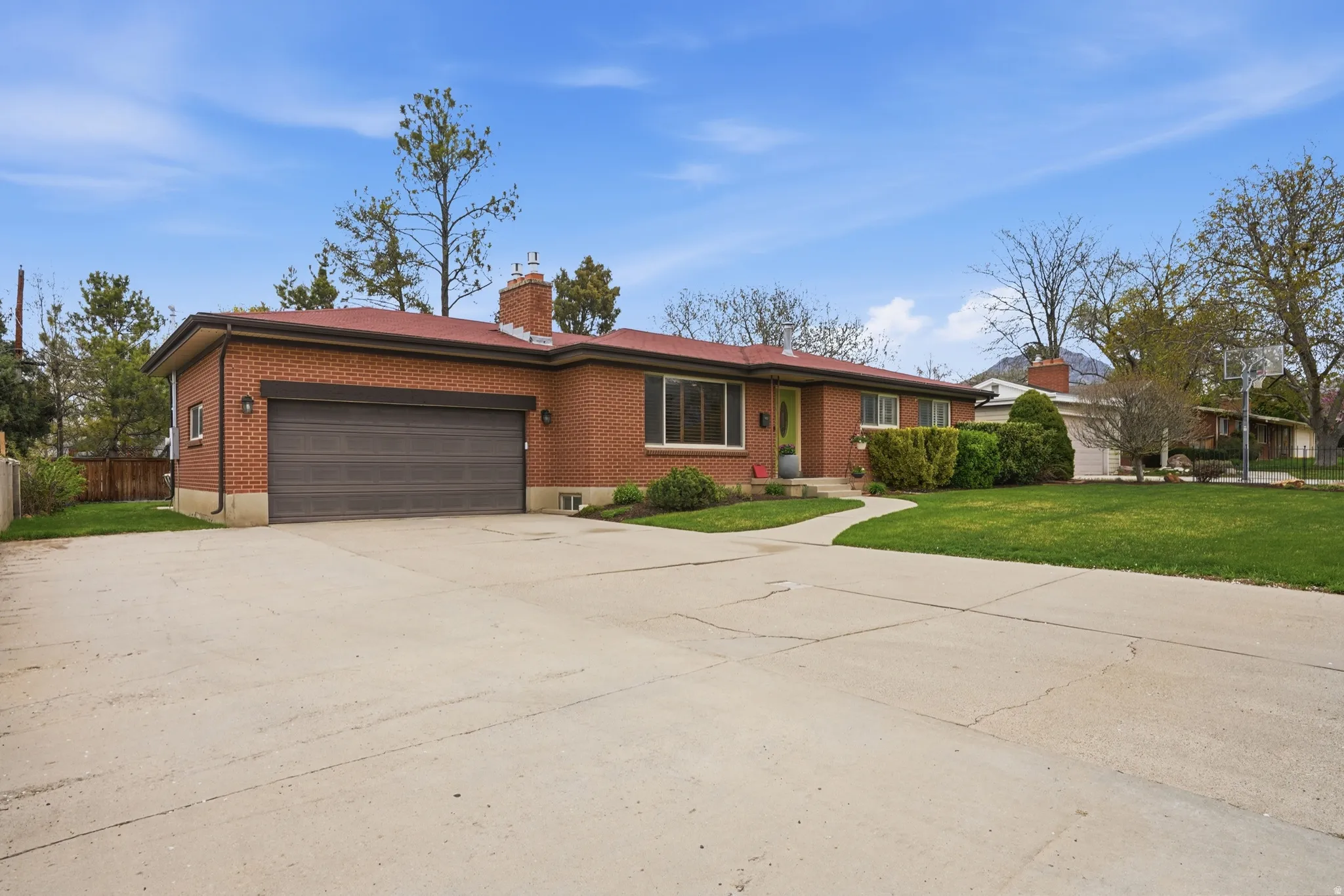 Rambler-style home featuring brick siding, a garage, concrete driveway, and a chimney
