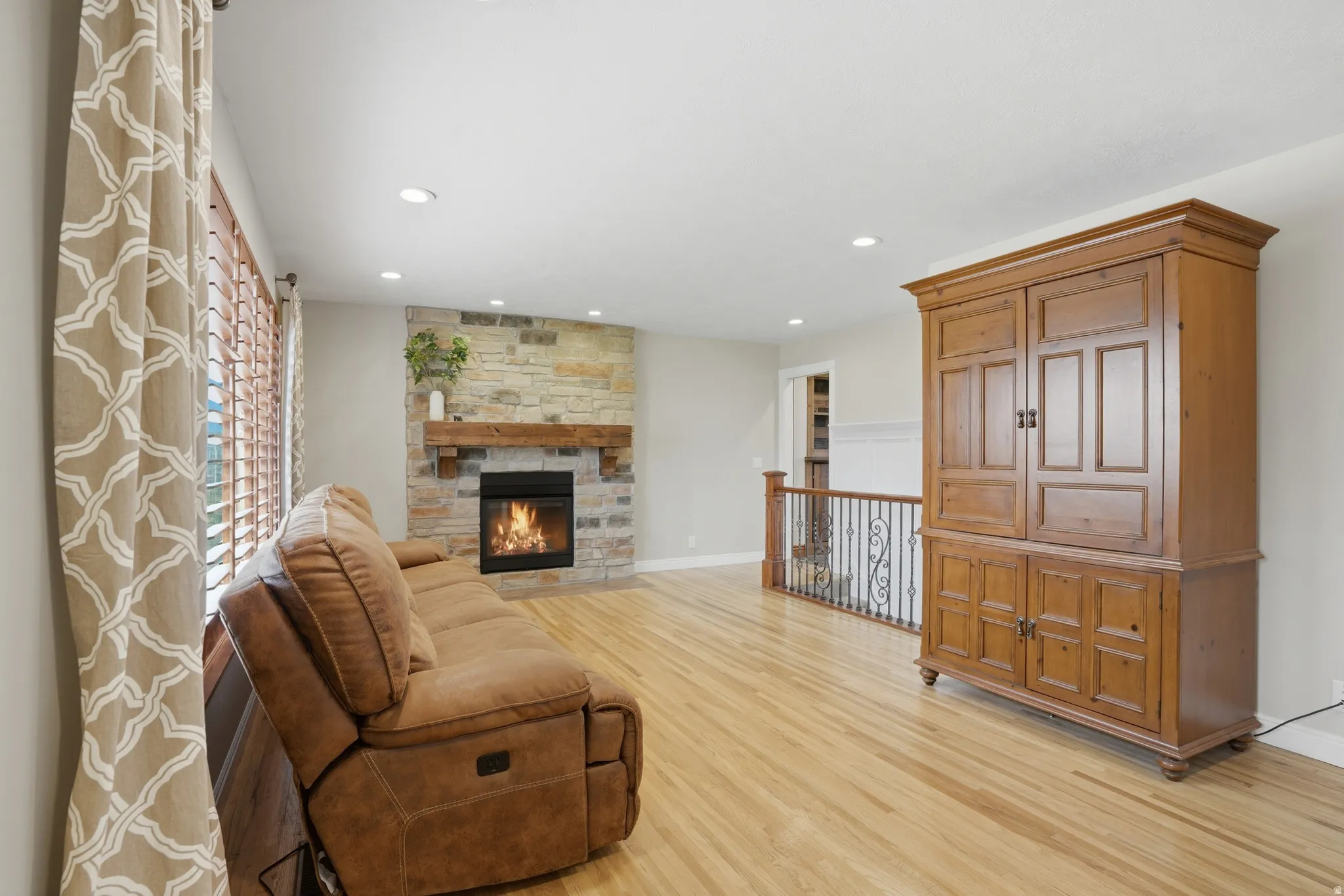 Living area featuring light wood-style flooring, a fireplace, and recessed lighting