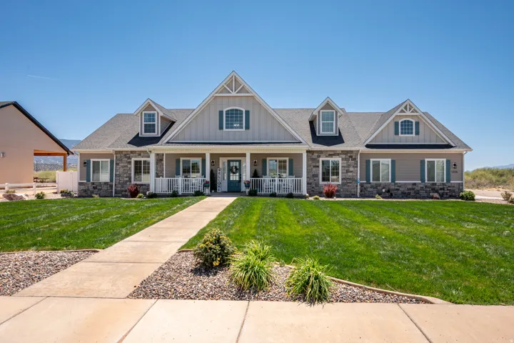 Craftsman-style home featuring a covered front porch with white railing, stone accents, horizontal siding, and dormer windows
