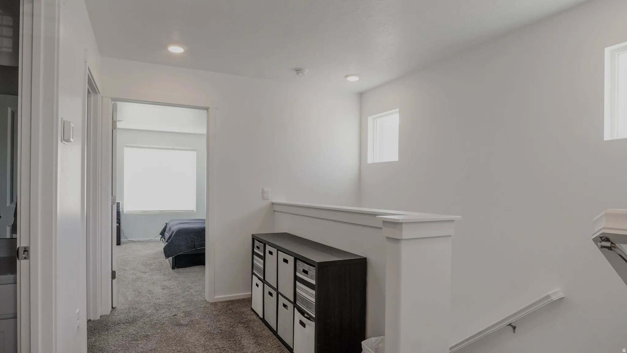 Corridor featuring an upstairs landing, light carpet, and plenty of natural light