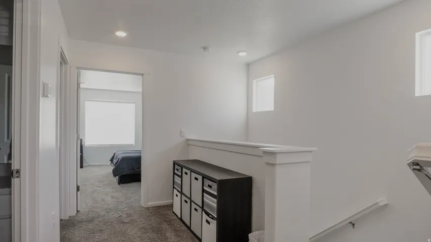 Corridor featuring an upstairs landing, light carpet, and plenty of natural light