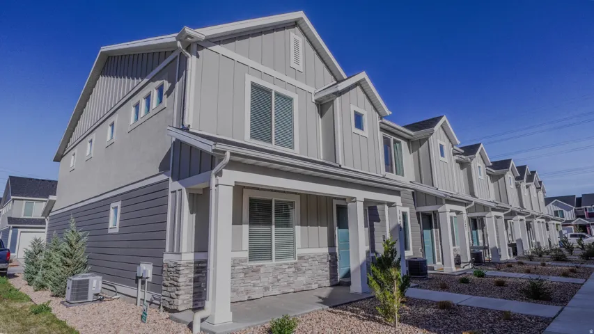 Modern townhome exterior featuring light gray vertical siding, dark gray horizontal siding, and stone veneer accents