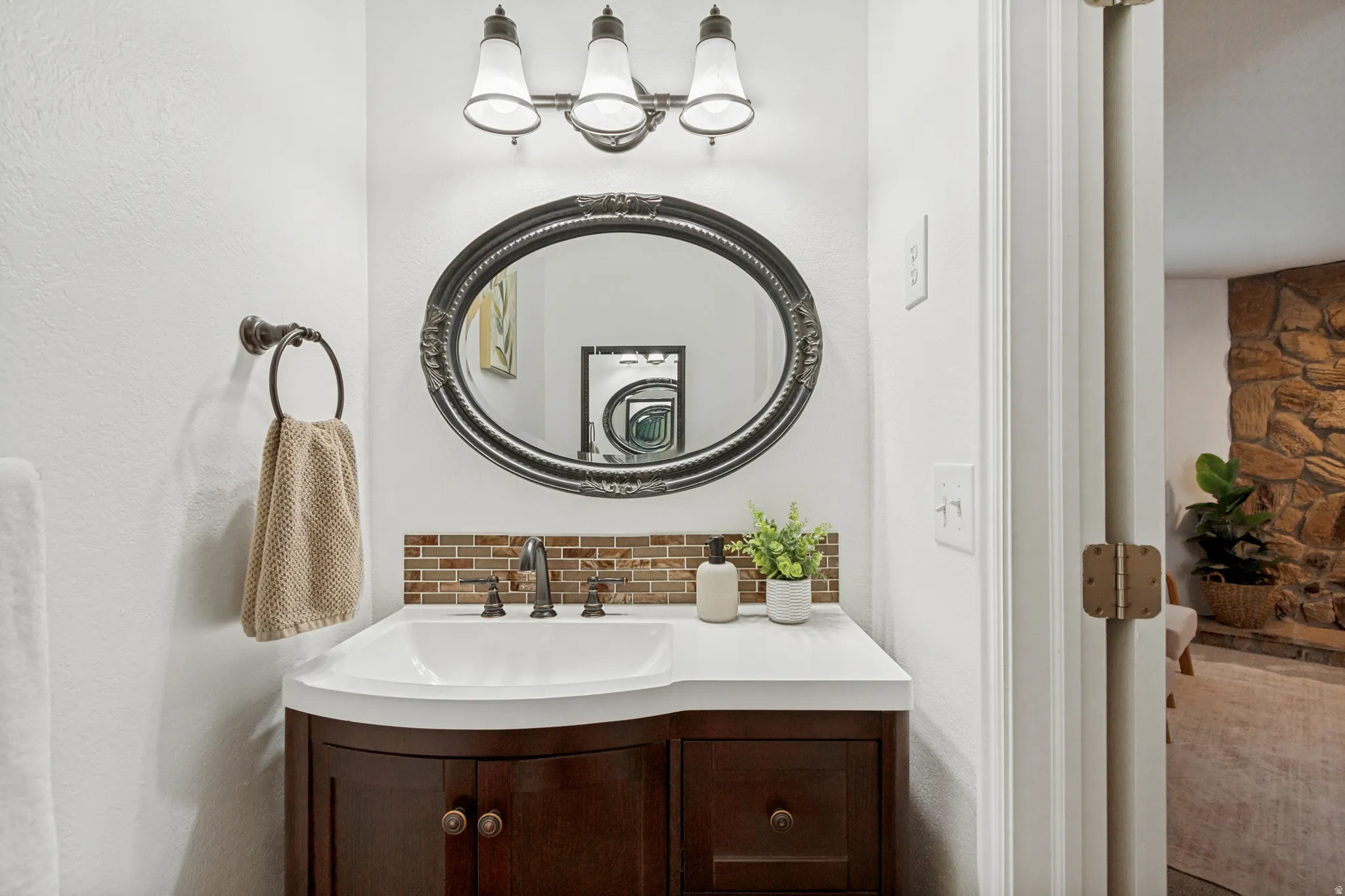 Bathroom vanity featuring a white countertop, under-mount sink, and dark wood-finish cabinetry