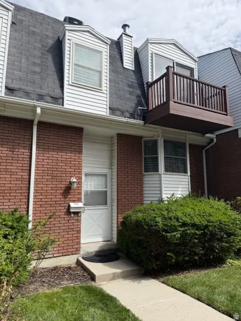 View of exterior entry with brick siding, a chimney, and roof with shingles