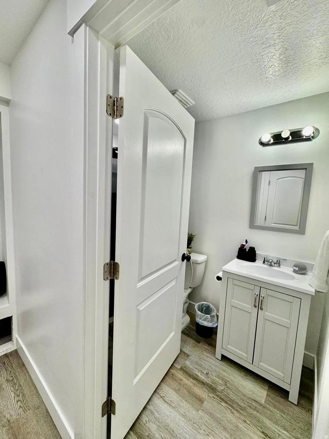 Bathroom with vanity, light wood-type flooring, and a textured ceiling