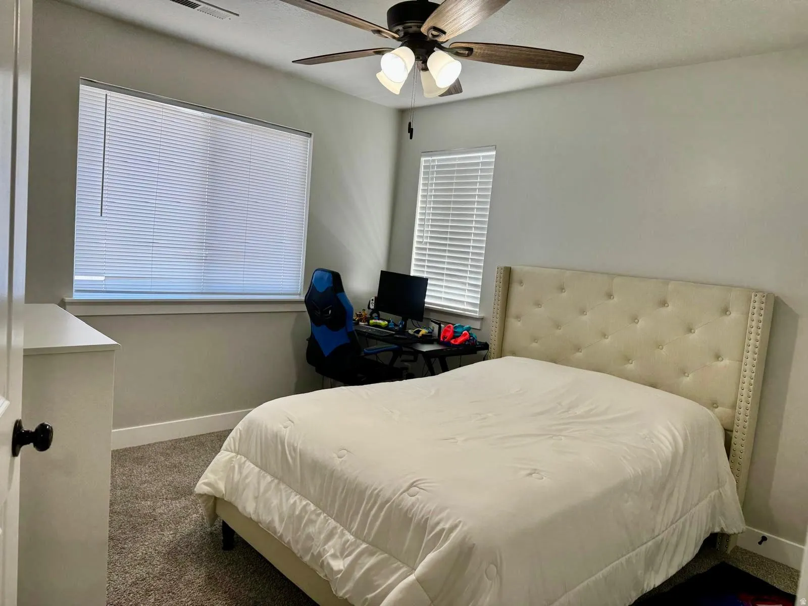Bedroom featuring dark carpet, ceiling fan, and multiple windows