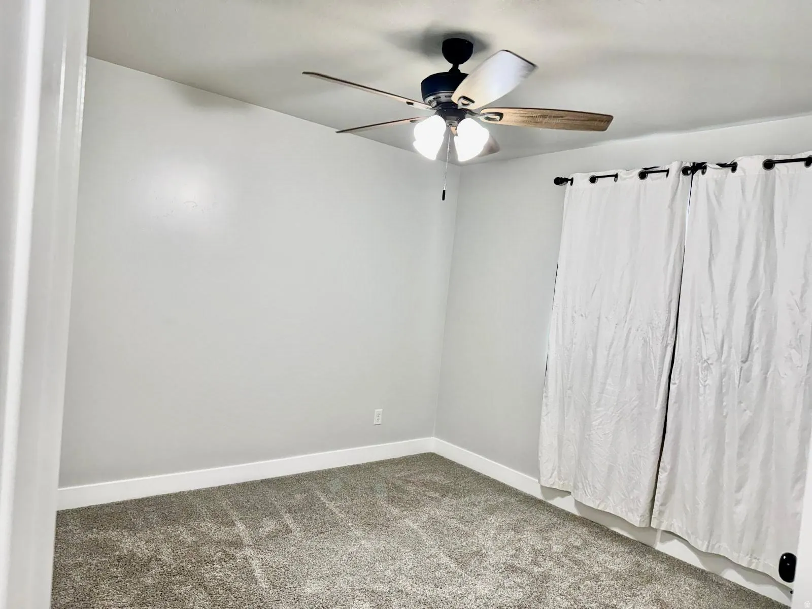 Empty room with dark colored carpet and ceiling fan