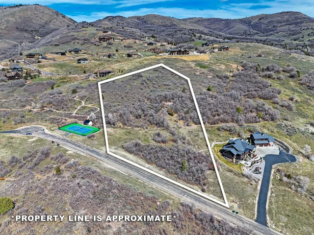 Aerial view of property and surrounding area with property parcel outlined and a mountain backdrop