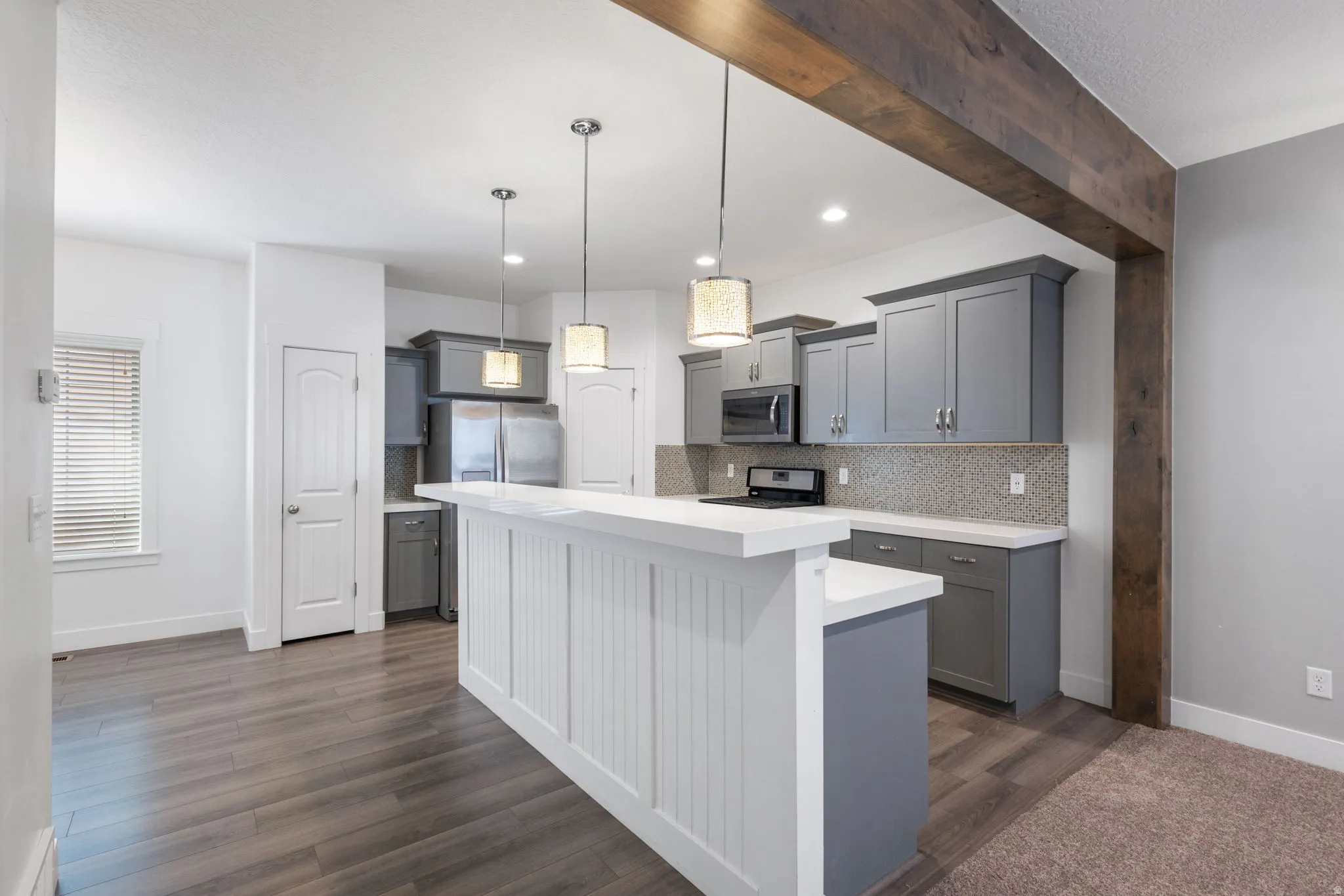 Kitchen with gray cabinets, tasteful backsplash, a center island, hanging light fixtures, and dark wood-style floors
