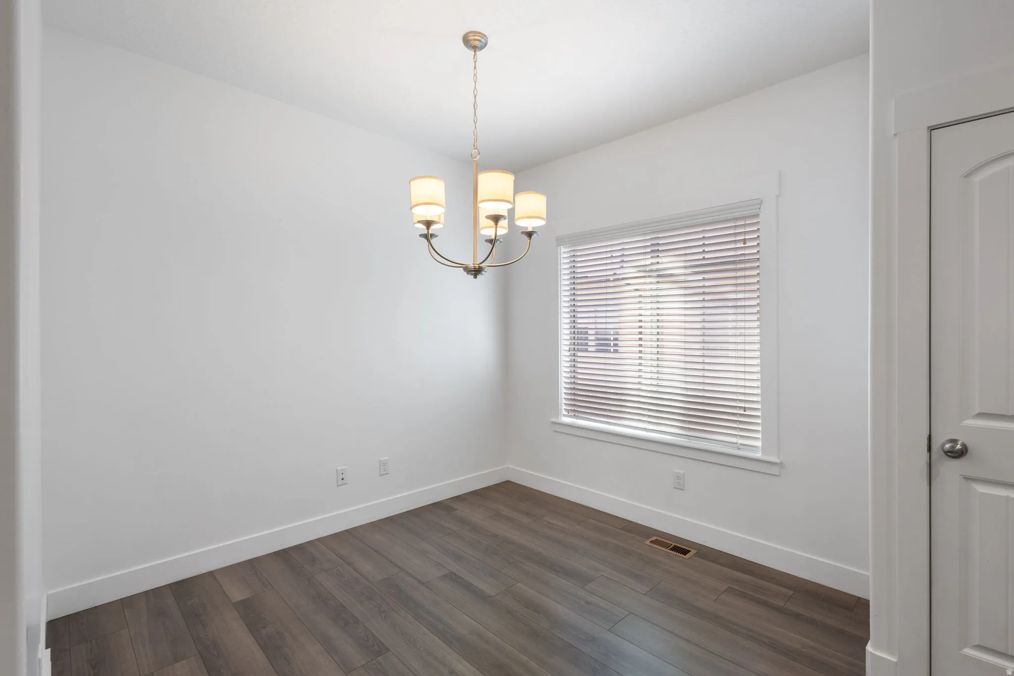 Unfurnished room with dark wood-style flooring and suspended lighting