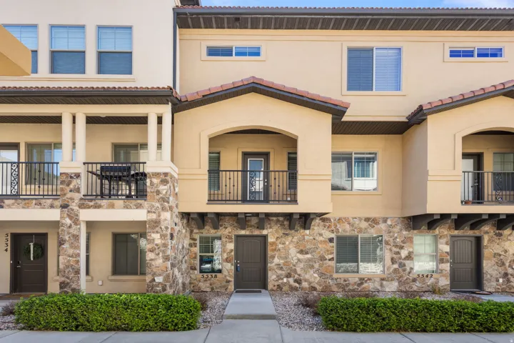 View of front of house with a balcony, stucco siding, stone siding, and a tile roof