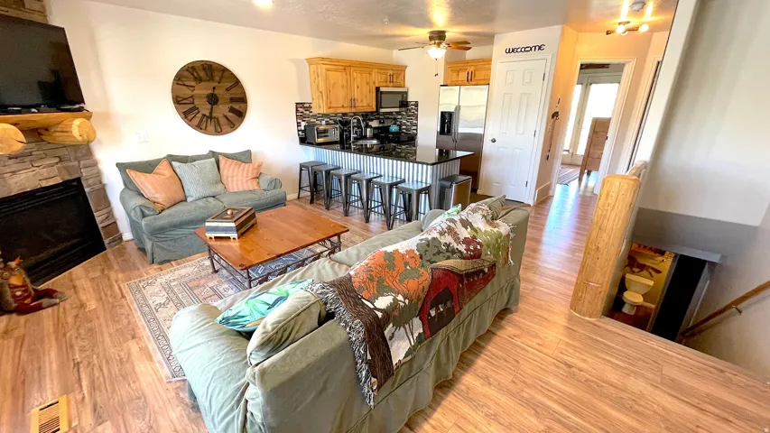 Living area with light wood-style flooring, a ceiling fan, and a fireplace