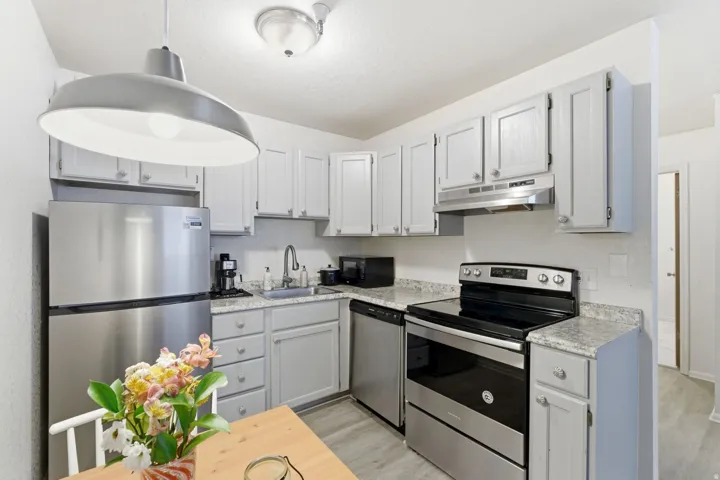 Kitchen with stainless steel appliances, light countertops, light wood-style floors, and gray cabinets