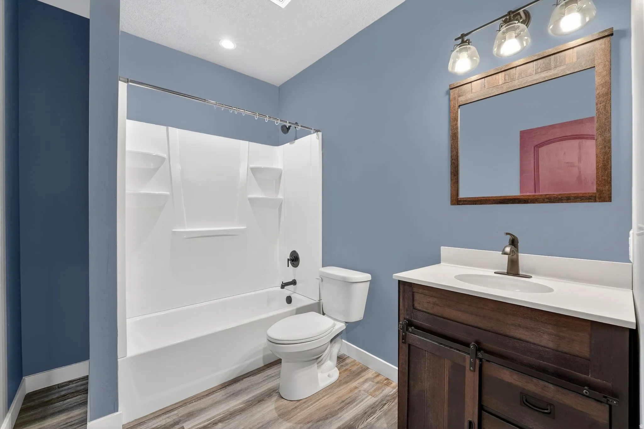 Bathroom with vanity, light wood-style flooring, and shower / tub combination