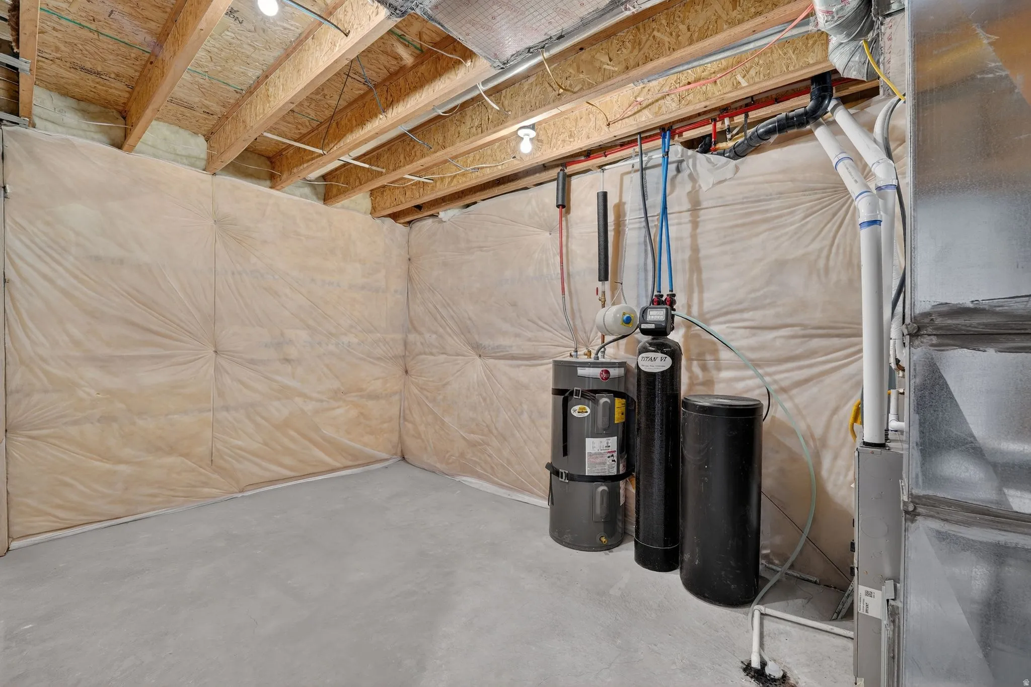 Unfinished basement featuring a water softener, water heater, and heating unit