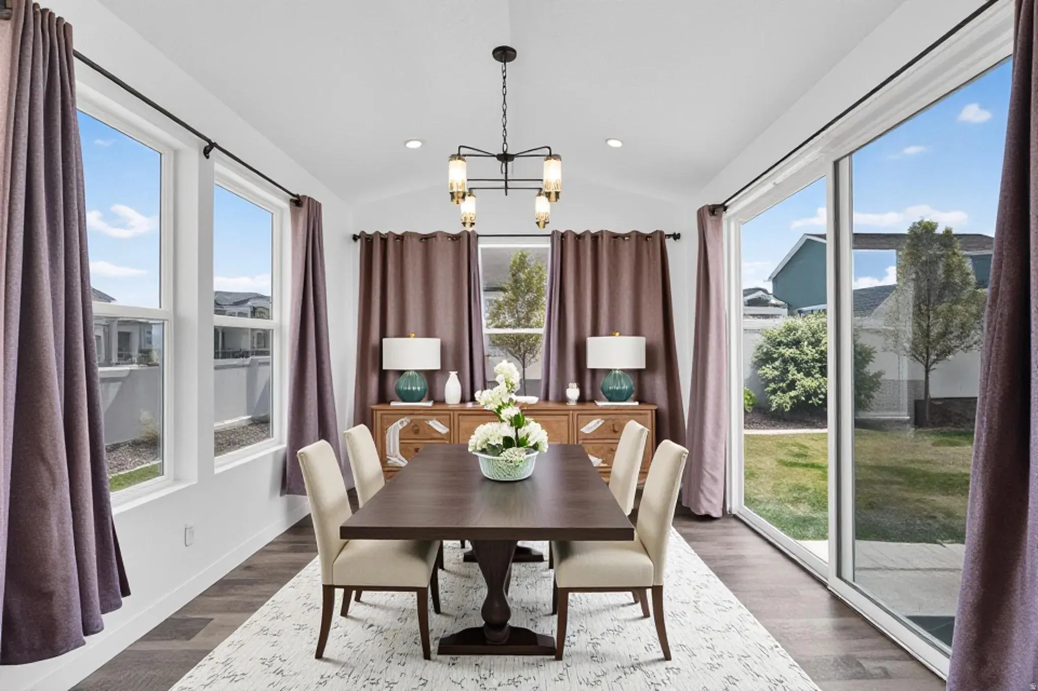Dining space with suspended lighting, wood finished floors, and vaulted ceiling