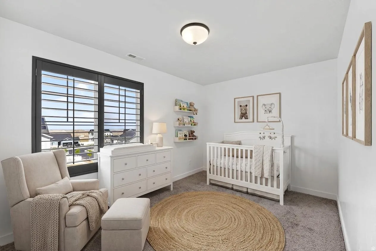 Bedroom with a nursery area and light carpet