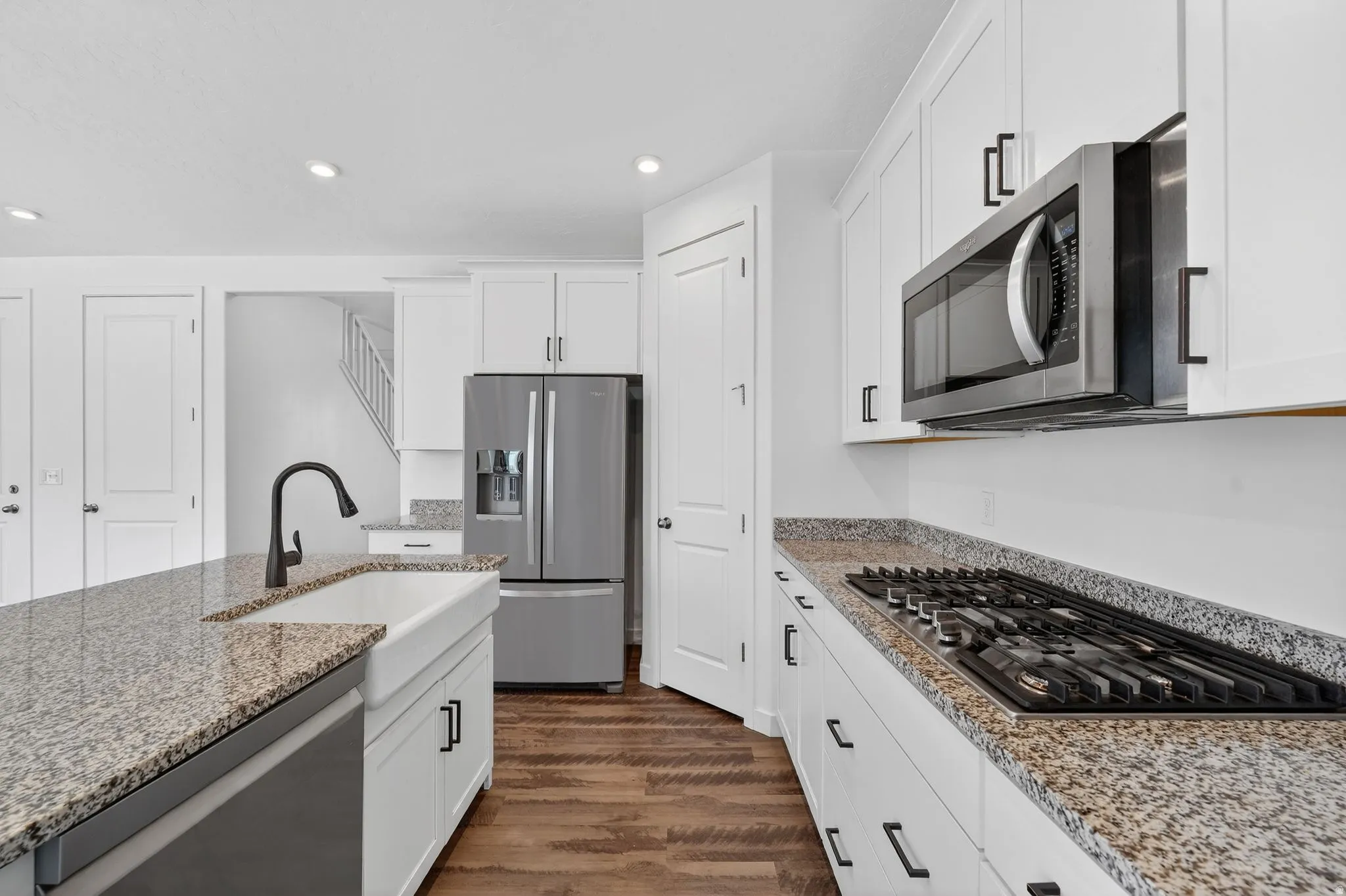 Kitchen with stainless steel appliances, light stone countertops, white cabinetry, and recessed lighting